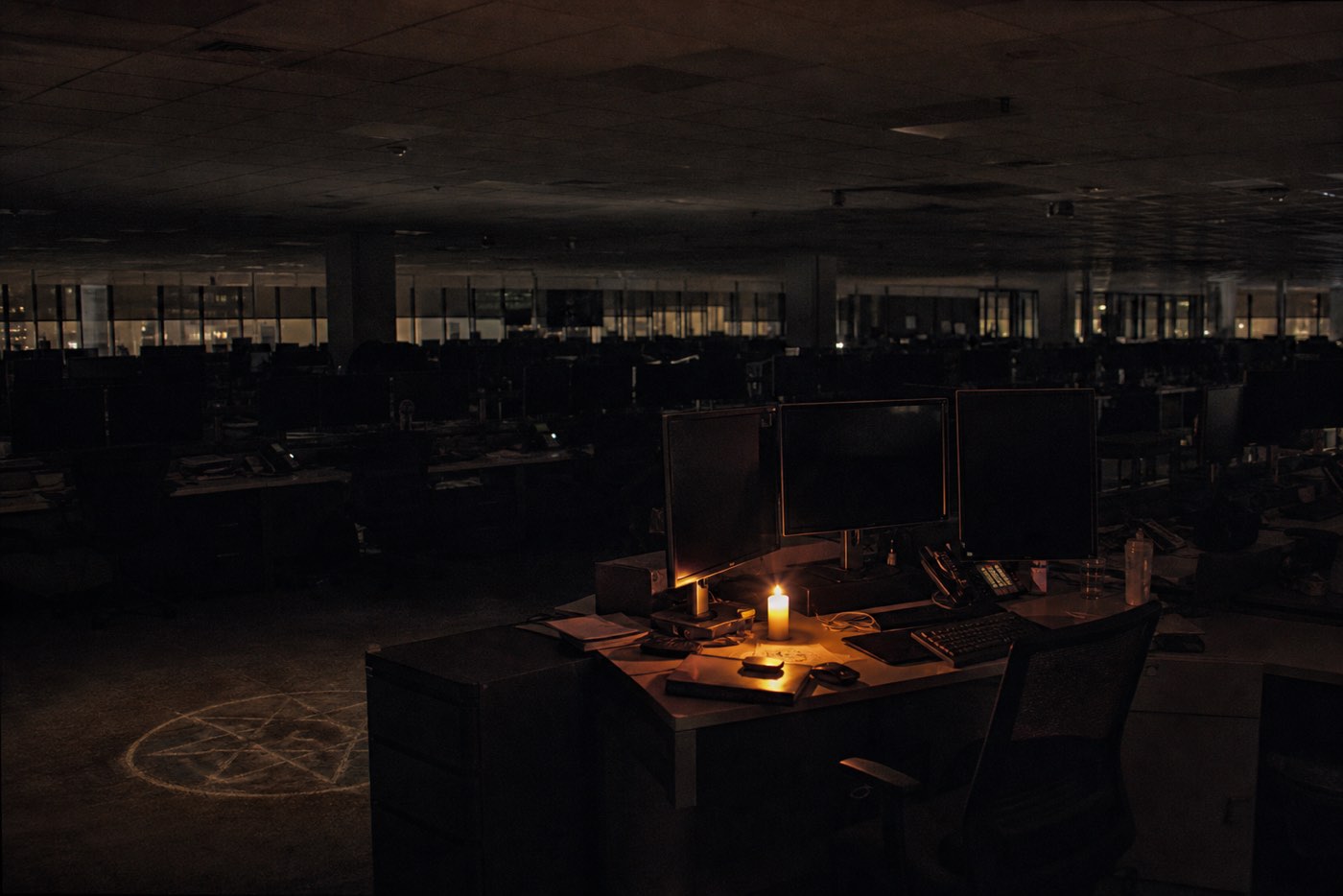 A trading floor after hours, screens still glowing over rows of empty desks.